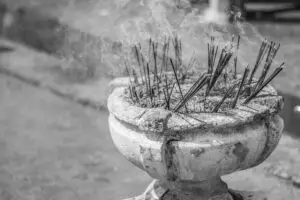 Black and white photo of incense sticks in a pot with smoke rising during a ritual.
